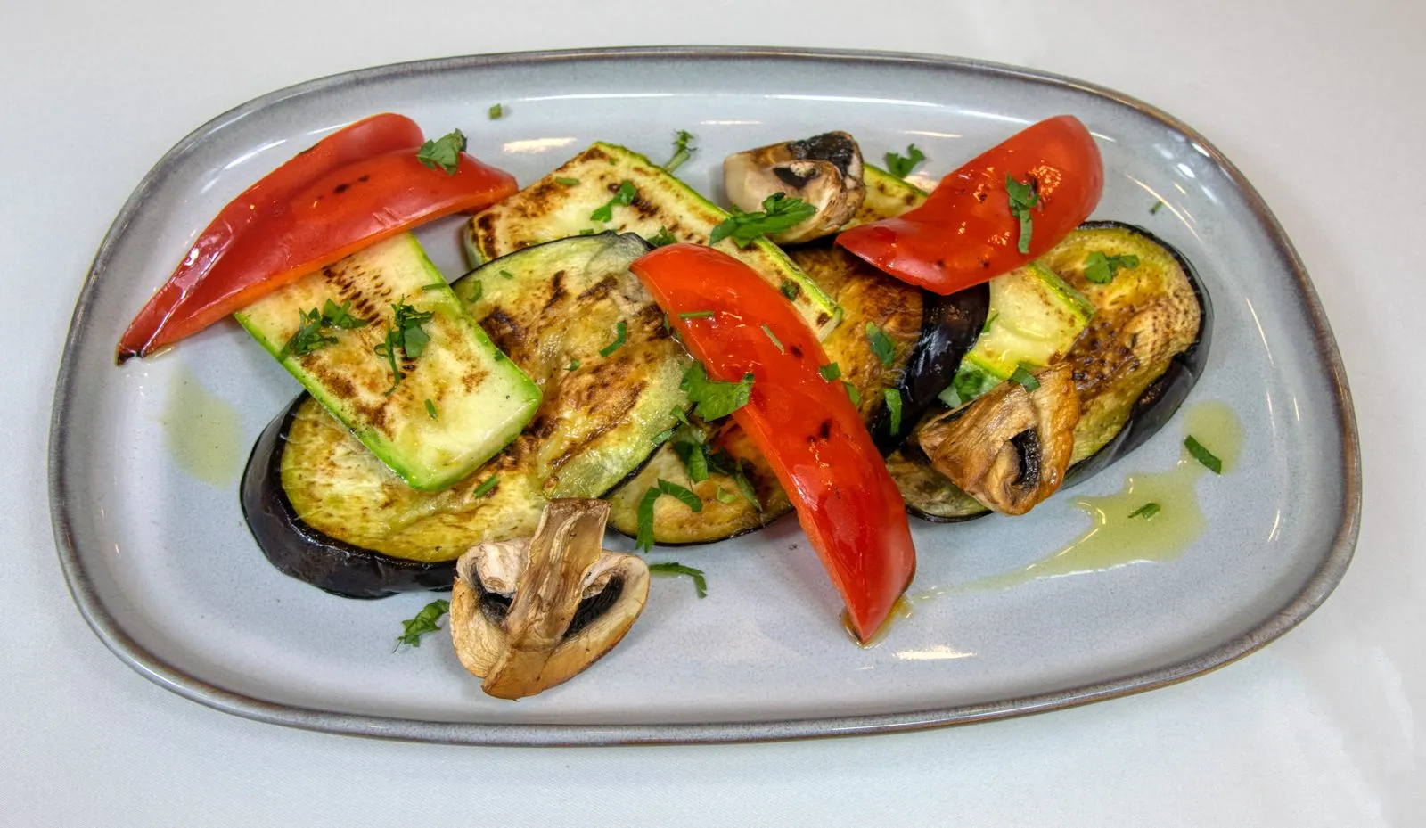 Delicious grilled vegetables with eggplant, zucchini, and red peppers on a plate.